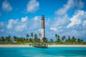 The Loggerhead Key Lighthouse on a beautiful beach with palm trees and crystal blue water in Dry Tortugas National Park